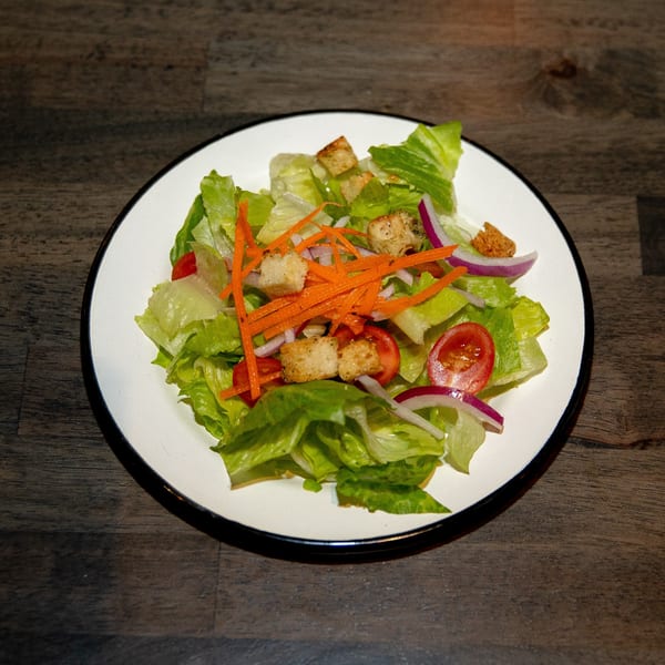 Fresh garden salad with lettuce, carrots, red onion, tomatoes, and croutons on a white plate.