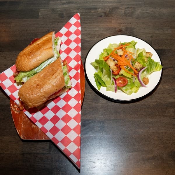 A Made from Skratch sandwich on checkered paper next to a fresh garden salad.